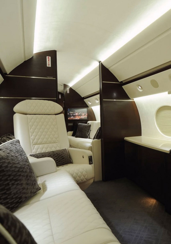 Business jet cabin interior with cream leather seats and dark wood panels